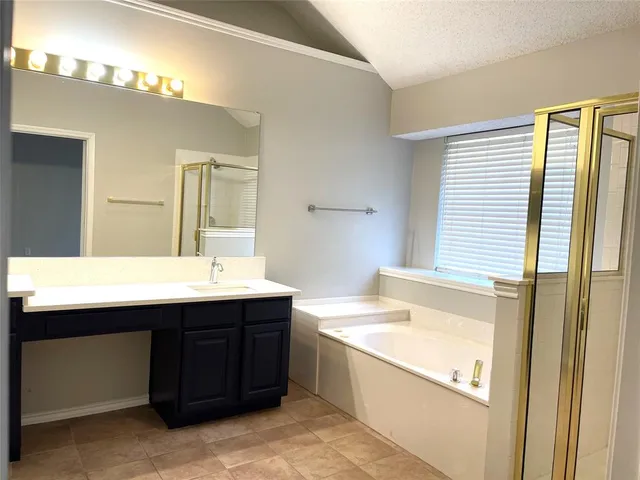a spacious bathroom with a granite countertop sink a bathtub and next to a window
