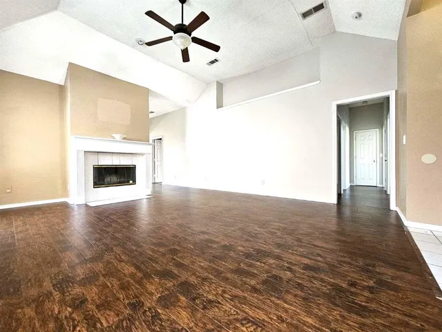 a view of a livingroom with a fireplace a ceiling fan and wooden floor