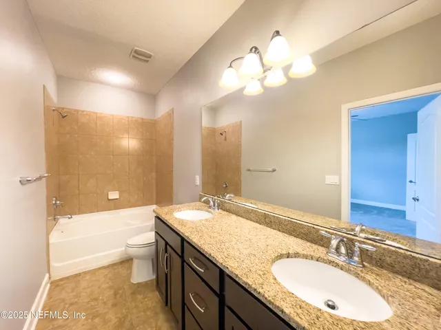a bathroom with a granite countertop sink a toilet and bathtub