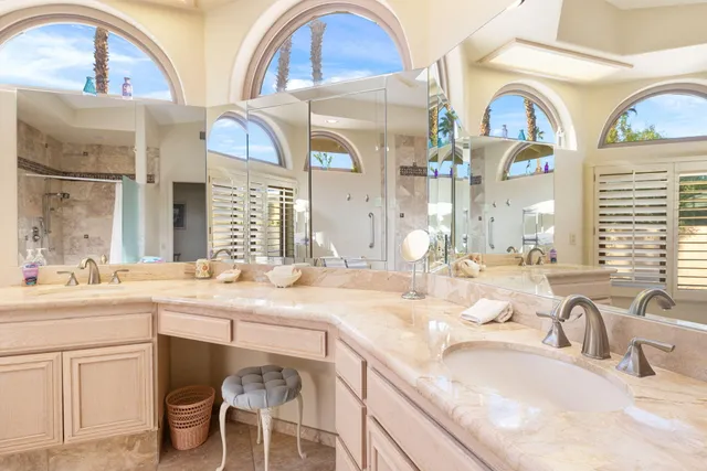 a bathroom with a granite countertop double vanity sinks a mirror and a window