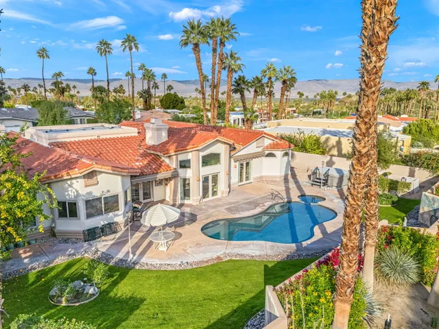 a view of a white house with a yard table and chairs