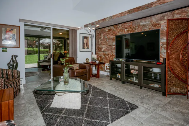 a living room with furniture a flat screen tv and floor to ceiling window