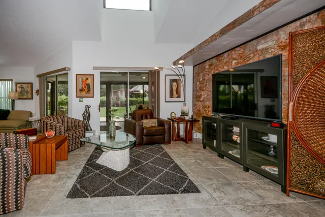 a living room with furniture a flat screen tv and a floor to ceiling window