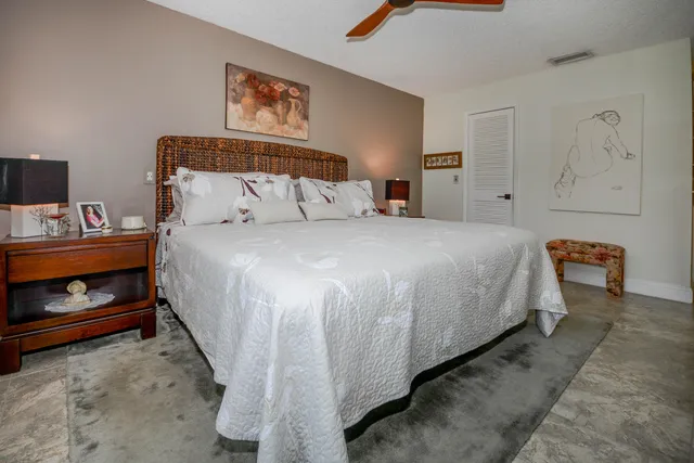 a spacious bedroom with a bed and a lamp on table