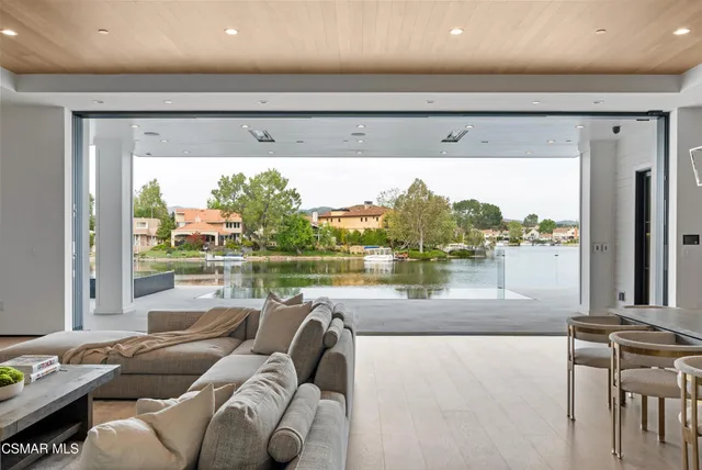 a large kitchen with kitchen island a large window a sink and white cabinets