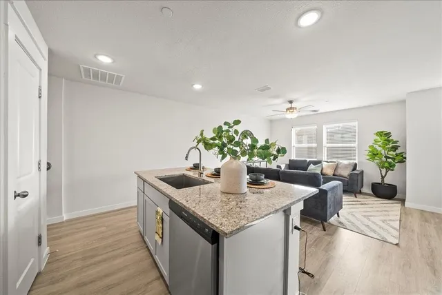 a kitchen with granite countertop a sink and a white cabinets