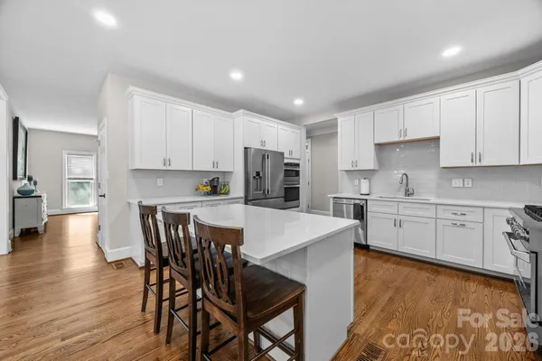 a kitchen with stainless steel appliances granite countertop a stove a sink a refrigerator with a dining table and chairs