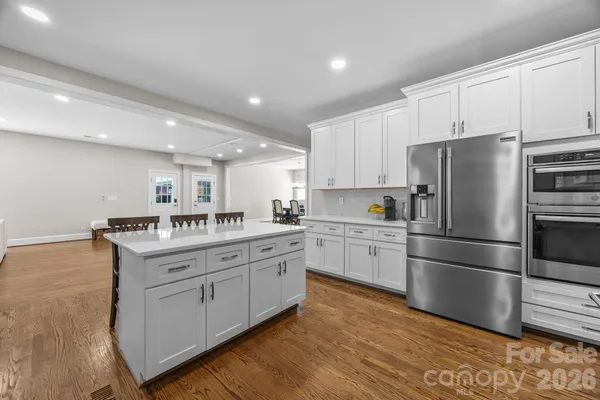 a kitchen with stainless steel appliances granite countertop a refrigerator sink and white cabinets