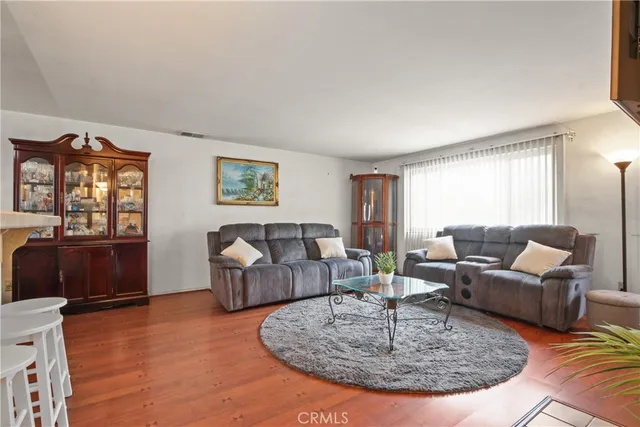a living room with couches couches and a dining table with wooden floor