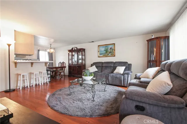 a living room with furniture and a dining table with wooden floor