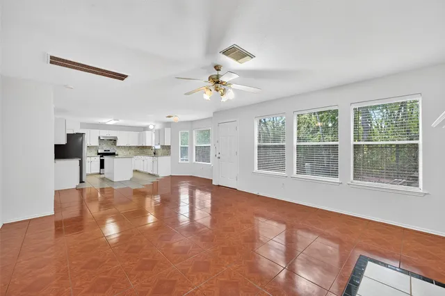 a view of an empty room with a kitchen and a window