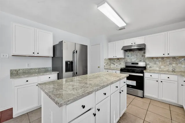 a kitchen with granite countertop a sink stove and cabinets