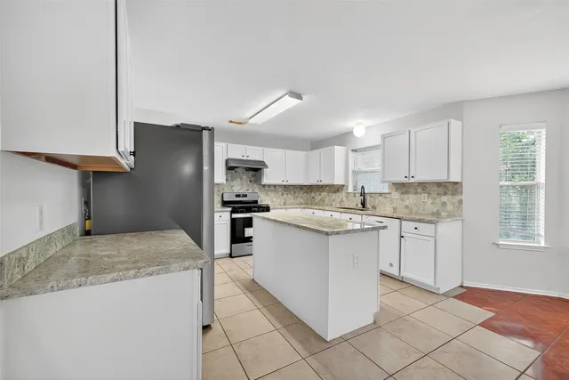 a kitchen with granite countertop white cabinets and stainless steel appliances