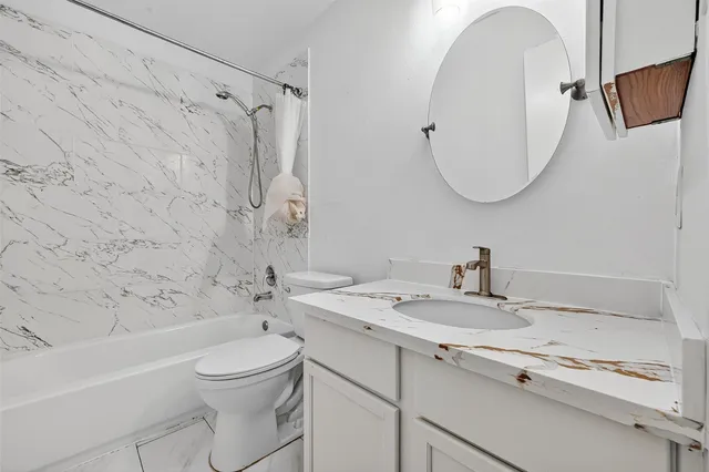a bathroom with a granite countertop sink a toilet and a mirror