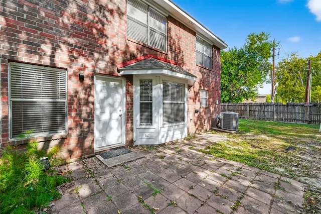 a view of a brick house with large windows and a small yard