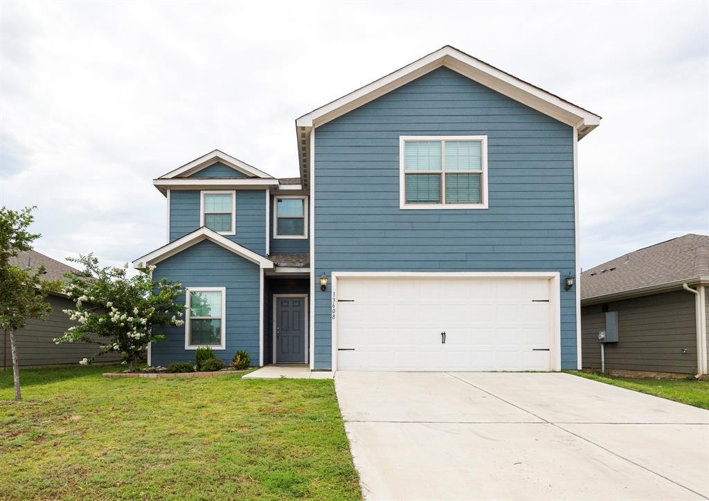 View of front of home featuring an attached garage, concrete driveway, and a front lawn