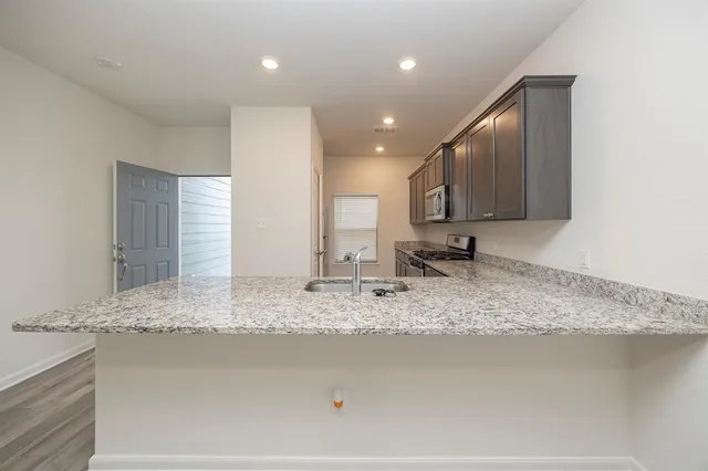 a view of kitchen with kitchen island granite countertop sink and stove