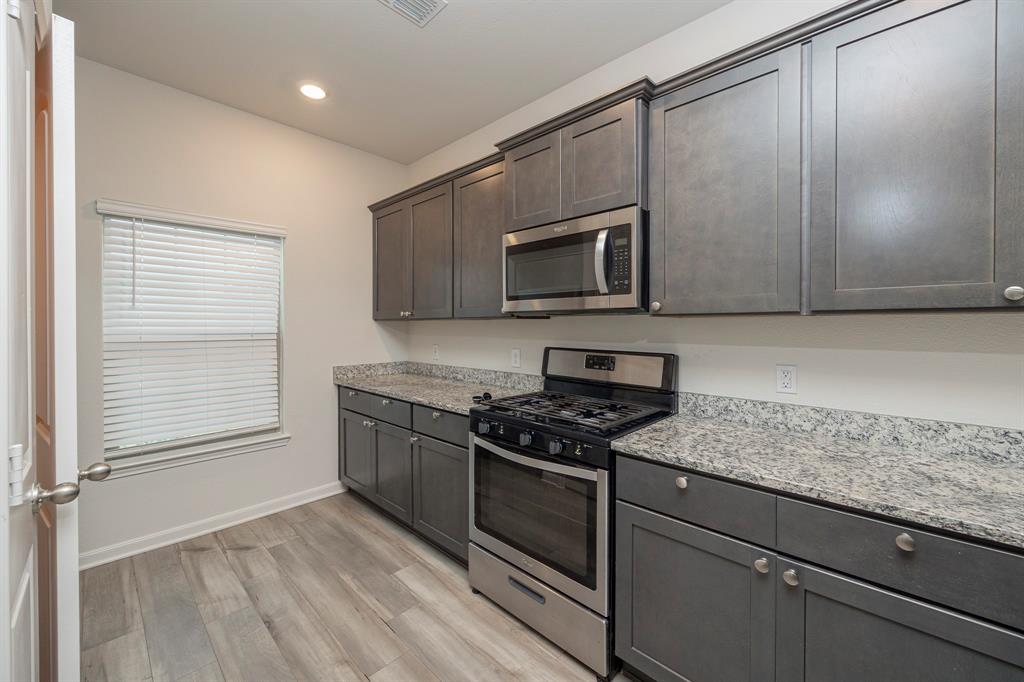 13608 Mineral Road Ponder, TX 76259 - Photo 9 of 36 Kitchen with appliances with stainless steel finishes, light wood finished floors, light stone countertops, recessed lighting, and dark brown cabinetry