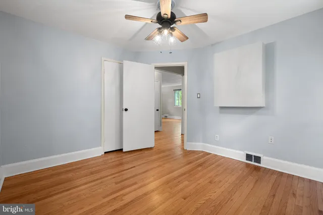 an empty room with wooden floor and a ceiling fan