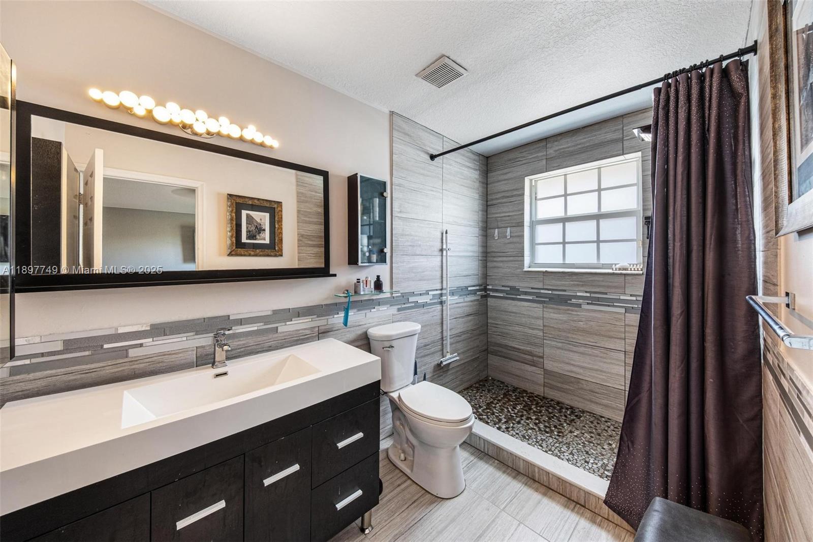 3869 Northwest 92nd Avenue Sunrise, FL 33351 - Photo 23 of 40 a bathroom with a toilet a sink a mirror and a shower