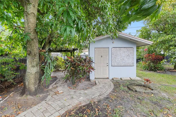 a backyard of a house with plants and large tree