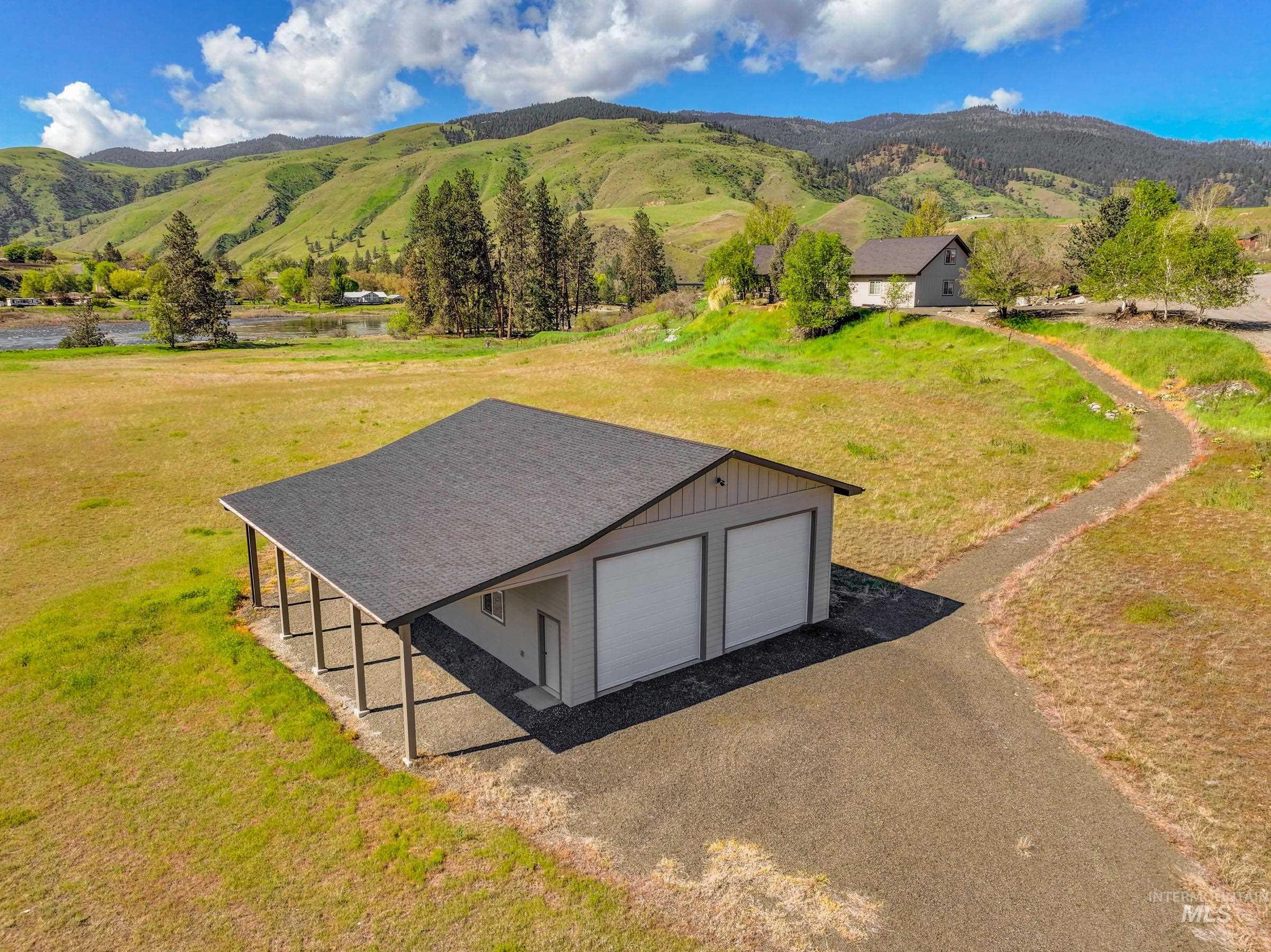 113 Deford Road White Bird, ID 83554 - Photo 45 of 49 Detached two-car garage with covered side patio, gravel driveway, and surrounding green landscape