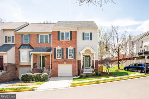 a view of a white house with a large windows and a yard with plants and large trees