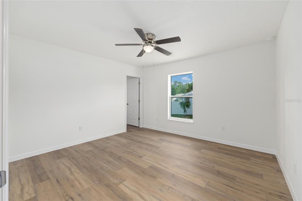 13031 Northeast 7th Loop Silver Springs, FL 34488 - Photo 20 of 34 an empty room with wooden floor ceiling fan and windows
