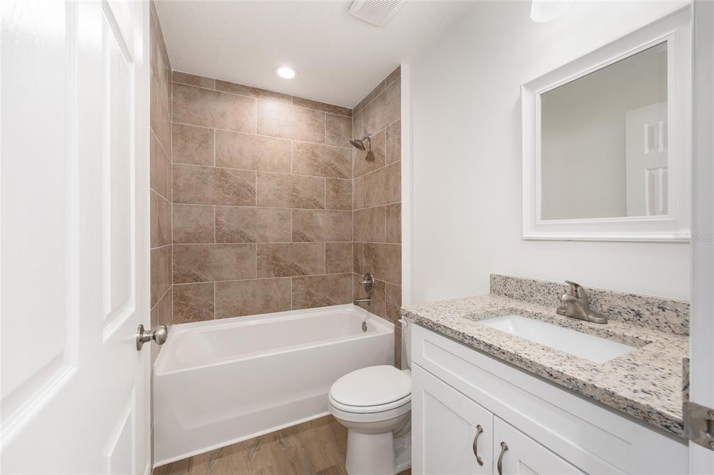13031 Northeast 7th Loop Silver Springs, FL 34488 - Photo 26 of 34 a bathroom with a granite countertop toilet a sink and a bathtub