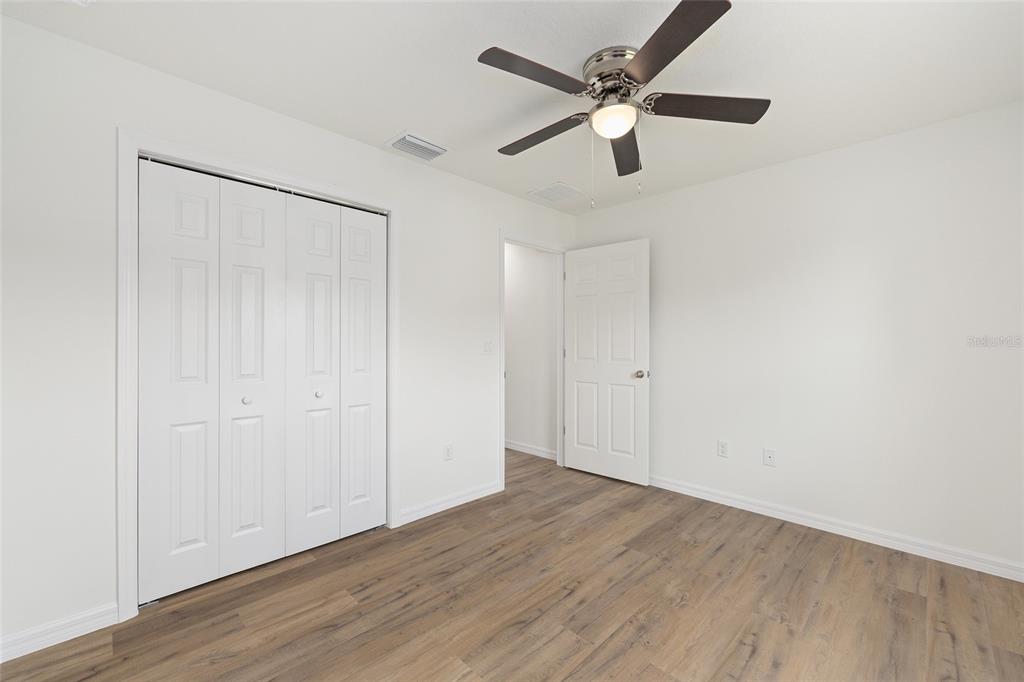 13031 Northeast 7th Loop Silver Springs, FL 34488 - Photo 28 of 34 an empty room with wooden floor ceiling fan and windows