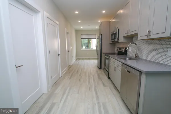 a view of a kitchen with a sink and dishwasher a refrigerator with wooden floor