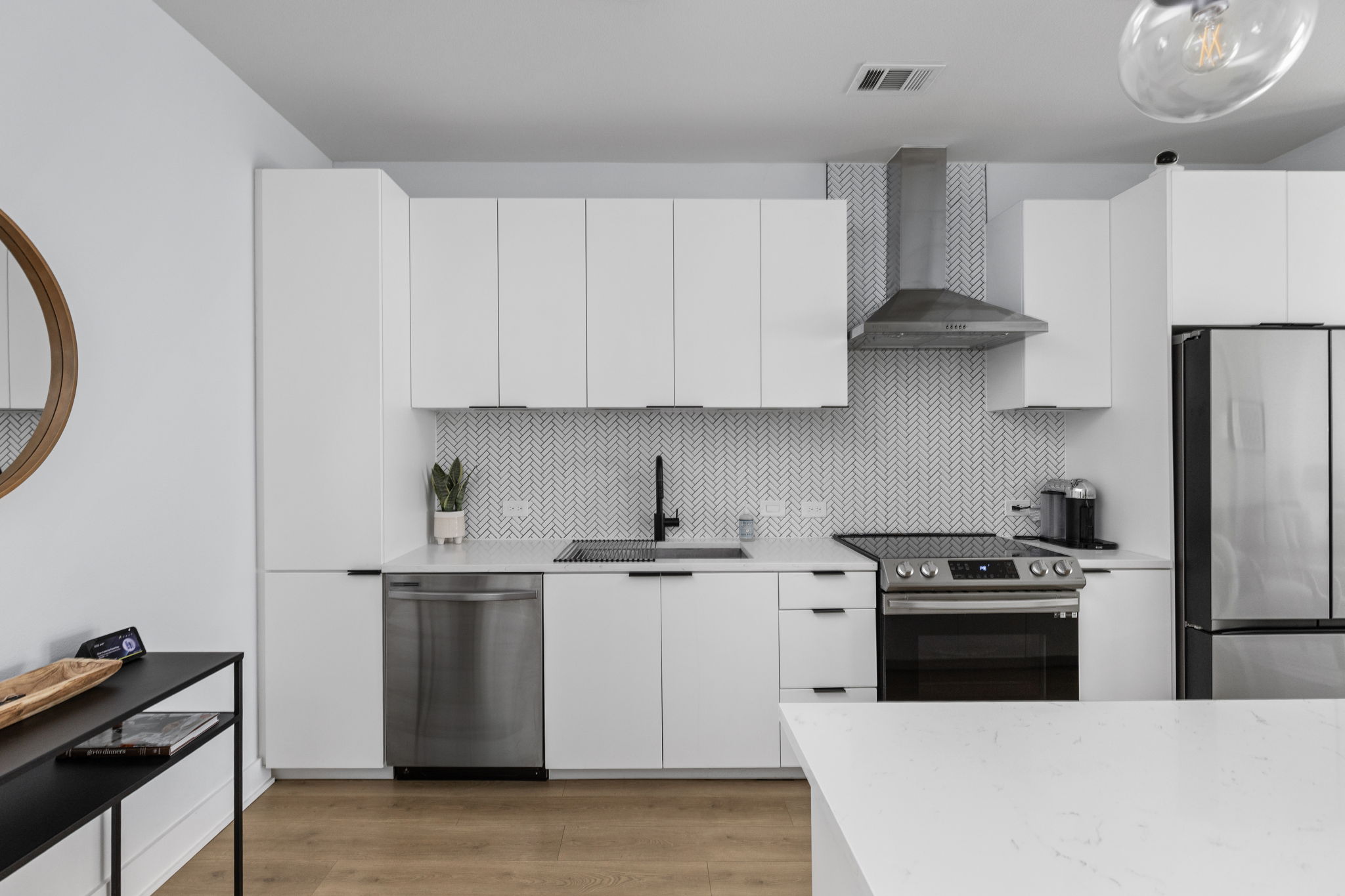 2500 Longview Street, Unit 507 Austin, TX 78705 - Photo 14 of 37 Modern kitchen with white cabinetry, stainless steel appliances, and a herringbone tile backsplash.