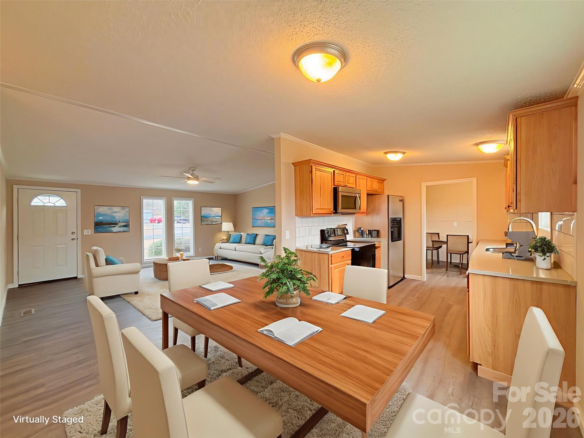 a view of a dining room and livingroom with furniture wooden floor a rug and a kitchen
