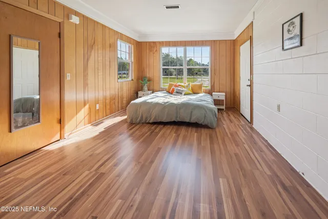 a spacious bedroom with a bed and wooden floor