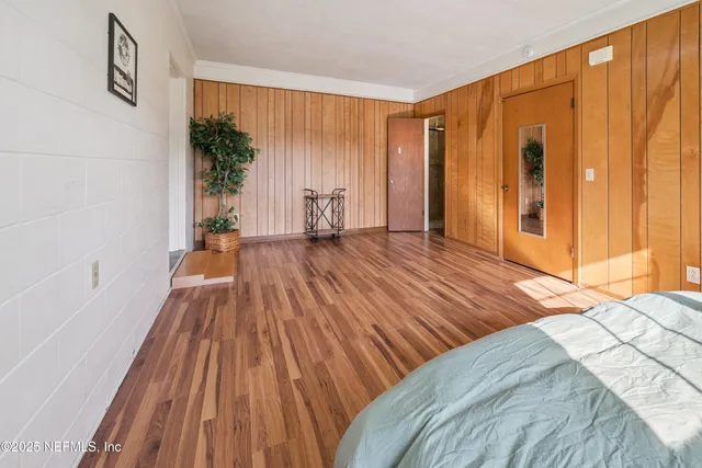 a view of a bedroom with wooden floor and windows