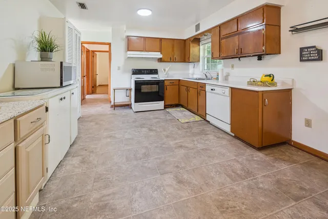 a large kitchen with stainless steel appliances granite countertop a stove top oven a sink a counter space and cabinets