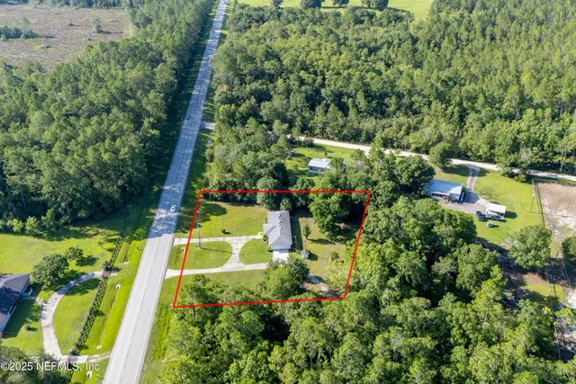 an aerial view of a house with a yard lawn chairs and large tree
