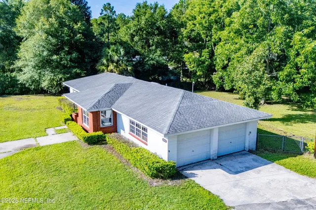 an aerial view of a house next to a big yard with large tree