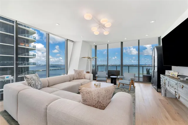 a living room with furniture a flat screen tv and a floor to ceiling window