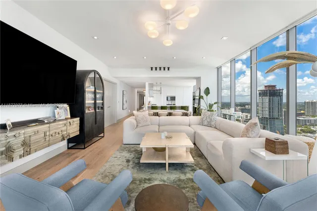 a living room with furniture a flat screen tv and a large window