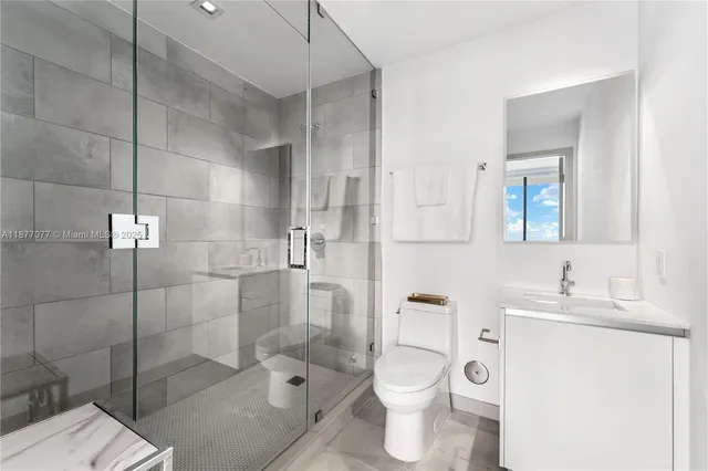 a bathroom with a toilet sink vanity granite and shower