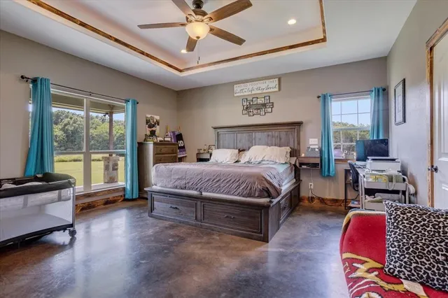 a spacious bedroom with a bed a couch and a chandelier fan