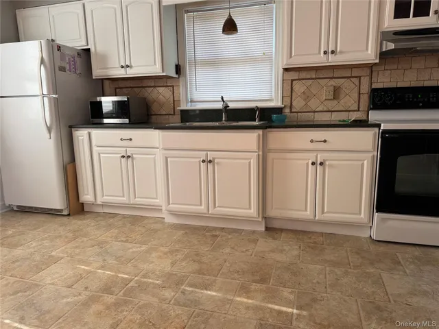 a kitchen with granite countertop a sink cabinets and stainless steel appliances