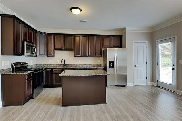 a kitchen with stainless steel appliances granite countertop a refrigerator stove top oven and wooden floors
