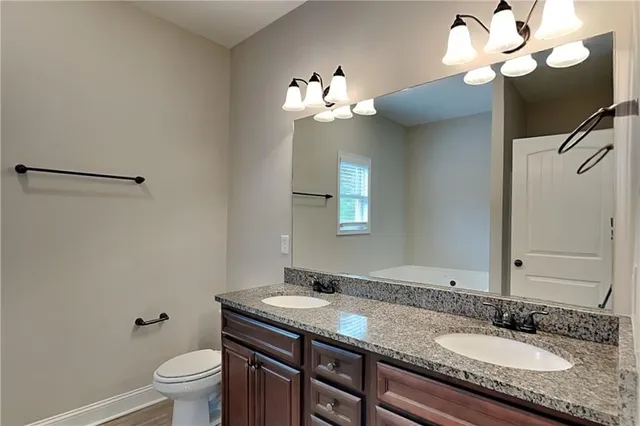a bathroom with a granite countertop sink a toilet and a mirror