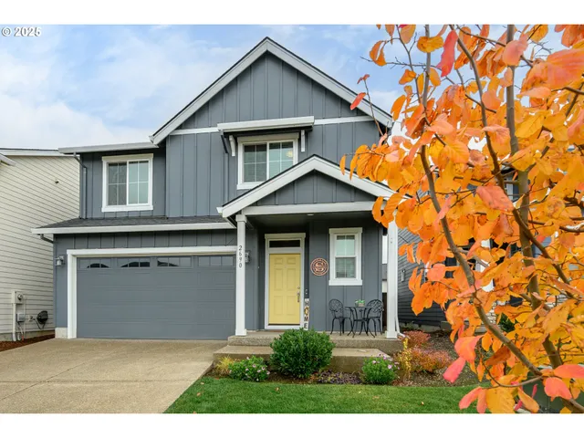 a view of a yard in front of a house with a large tree