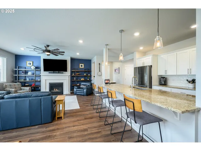 a open kitchen with stainless steel appliances kitchen island granite countertop a refrigerator a stove a sink and a dining table with wooden floor