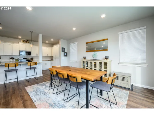 a room with stainless steel appliances dining table wooden floor and a view of kitchen