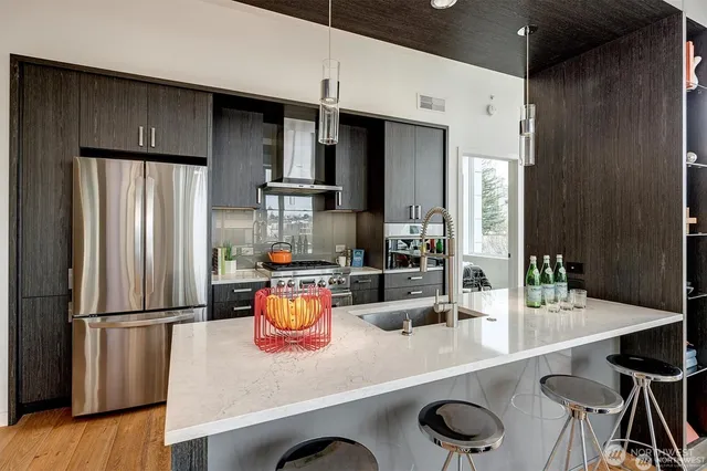 a kitchen with stainless steel appliances a sink a refrigerator and a counter space