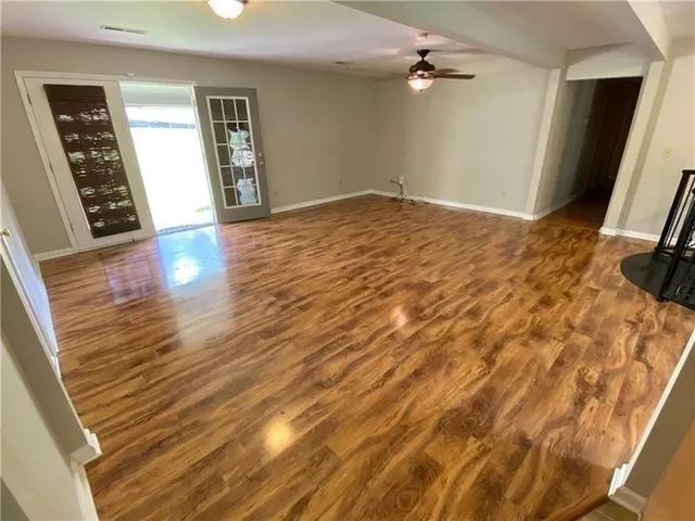 a view of empty room with wooden floor and fan